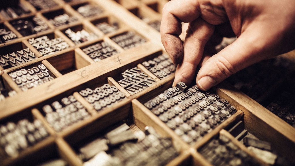 Man choosing type face for old printing press